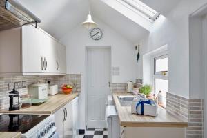 a kitchen with white cabinets and a clock on the wall at The Skiff in Deal