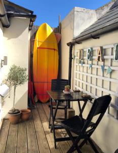 a table and chairs on a balcony with a surfboard at The Skiff in Deal