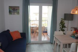 ein Wohnzimmer mit einem Sofa und einem Tisch sowie einem Balkon in der Unterkunft Apartamentos Vado - Arco de Elvira in Granada