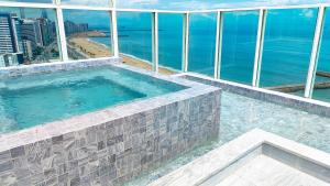 a swimming pool on top of a building overlooking the ocean at Seara Praia Hotel in Fortaleza