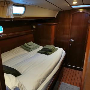 ハーシュタにあるWeekend liveaboard sailing tourのボートのベッドの上に緑のタオルが2枚敷かれている
