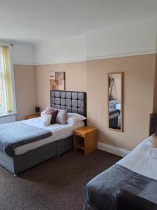 a hotel room with two beds and a mirror at Sheridans Budget Accomodation in Wallasey