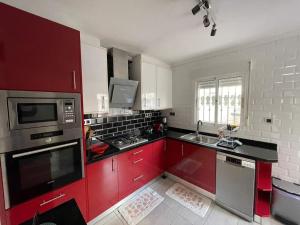 La cuisine est équipée de placards rouges et d'un four avec plaques de cuisson. dans l'établissement Casa Sortino Rizzo, à San Miguel de Salinas