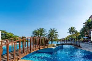 a bridge over a pool at a resort at Flat em resort - pé na areia, Camboinhas in Niterói