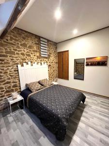 a bedroom with a bed and a stone wall at Gîte l'étable détente SALLE SPA EN SUPPLEMENT in Vautorte