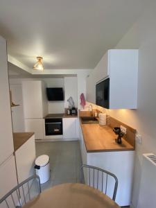 a kitchen with white cabinets and a sink and a table at Appartement Confort in Vélizy-Villacoublay