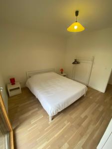 a bedroom with a white bed and a yellow light at Appartement Confort in Vélizy-Villacoublay