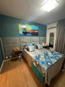 um quarto com uma cama e um quadro na parede em Flat em resort - pé na areia, Camboinhas em Niterói