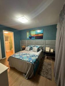 um quarto com uma cama e uma parede azul em Flat em resort - pé na areia, Camboinhas em Niterói