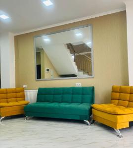 a waiting room with a green couch and two orange chairs at Hotel Saba in Rustavi
