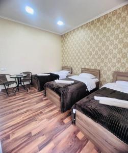Cette chambre comprend 3 lits et une table. dans l'établissement Hotel Saba, à Roustavi