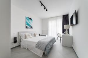 ein weißes Schlafzimmer mit einem weißen Bett und einem Tisch in der Unterkunft Southern Villas in Santa Maria di Leuca