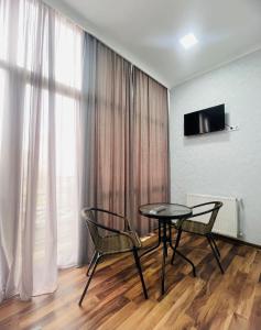 Habitación con mesa, 2 sillas y TV. en Hotel Saba, en Rustavi