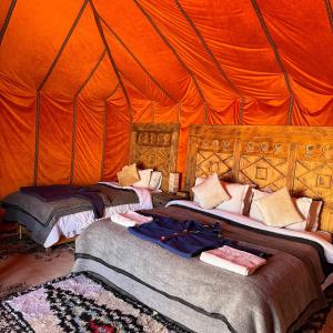 a bedroom with two beds in an orange tent at Authentic Luxury Camp in Merzouga