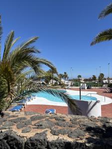 a swimming pool with a palm tree and a resort at Villa Palmeras in Costa Teguise