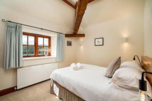 a bedroom with a white bed and a window at Blacksmiths cottage set on a peaceful farm in Buckinghamshire