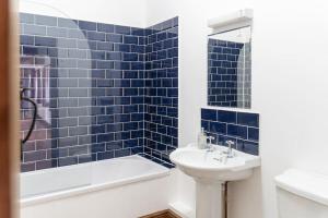 a blue tiled bathroom with a sink and a bath tub at Blacksmiths cottage set on a peaceful farm in Buckinghamshire