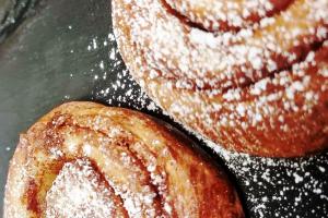 two donuts with powdered sugar on a plate at Guest Homes - Bakers Quay Apartment in Gloucester