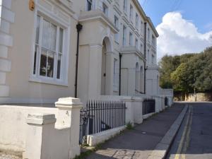 a white house with a fence and a street at 5 bed property in Hastings Sussex 57217 in Hollington