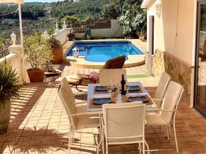 eine Terrasse mit einem Tisch, Stühlen und einem Pool in der Unterkunft 4 bedrooms villa with sea view private pool and furnished terrace at Callosa de Ensarria 9 km away from the beach in Callosa d'en Sarrià