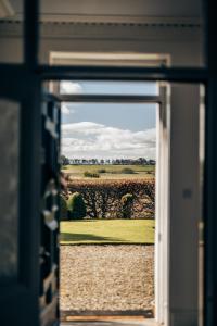 a view of a field through an open door at The Farmhouse - Countryside Escape with Hot Tub in Broughty Ferry