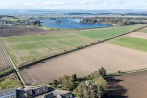 an aerial view of a field and a lake at The Farmhouse - Countryside Escape with Hot Tub in Broughty Ferry