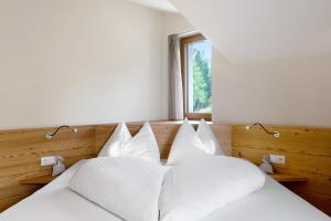 a bedroom with two beds with white pillows and a window at Furnerhof Apt Olpenglühn in Collepietra