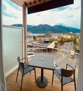 uma mesa e cadeiras numa varanda com vista para a cidade em Hotel Garni Montaldi em Locarno