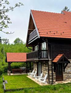 una casa con techo rojo y sillas blancas en Forest Hill kuća za odmor na Zlataru en Nova Varoš