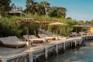 a row of lounge chairs and umbrellas on a dock at GAIA Alaçatı BY THE SEA - Adult Only in Cesme