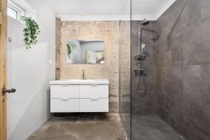 e bagno con doccia, lavabo e mobile con lavabo bianco. di Rauðafell ChickenCoop a Skogar Altre 5 foto