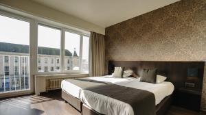 a hotel room with two beds and two windows at Hotel Ambassadeur in Ostend
