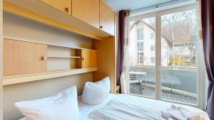 a bedroom with a bed and a large window at strandnahe FeWo mit Schwimmbad im Haus, a cappella 15, Binz in Binz