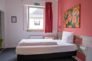 a bedroom with a bed with a pink wall at Honeybee Properties Winningen in Winningen