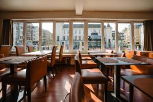 a restaurant with tables and chairs and a large window at Hotel Ambassadeur in Ostend