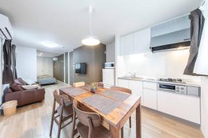 a kitchen and living room with a wooden table and chairs at Logement Aile 201 in Takasaki