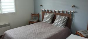 een slaapkamer met een bed met 2 kussens bij Maison agréable dans le Blayais in Cézac