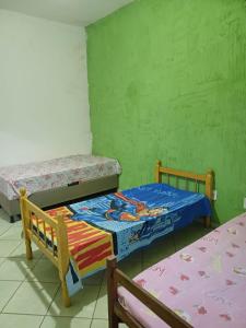 duas camas num quarto com paredes verdes em Casa Itaúnas em Itaúnas