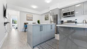 uma cozinha com electrodomésticos de aço inoxidável e armários brancos em Luxury Suite 4mins To Falls em Cataratas do Niágara