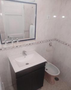 La salle de bains est pourvue d'un lavabo, de toilettes et d'un miroir. dans l'établissement Hotel Bela Vista, à Olhão