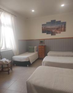 a hotel room with three beds and a window at Hotel Bela Vista in Olhão