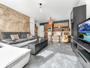 uma sala de estar com um sofá, uma televisão e uma cozinha em Homey Melody - Proche Centre, Parking, Wifi, Terrace em Annemasse