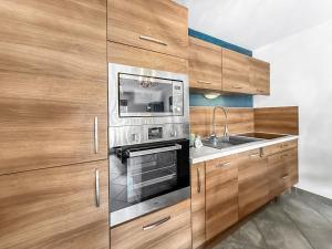 uma cozinha com armários de madeira e um forno de aço inoxidável em Homey Melody - Proche Centre, Parking, Wifi, Terrace em Annemasse