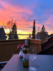 uma garrafa de vinho e um copo numa mesa com um pôr-do-sol em Gästehaus Herzog em Uhldingen-Mühlhofen