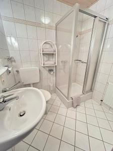 a white bathroom with a shower and a sink at Gästehaus Herzog in Uhldingen-Mühlhofen