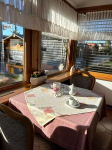 a table with a pink table cloth and a tea set in front of a window at Gästehaus Herzog am Bodensee in Uhldingen-Mühlhofen