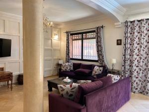 Villa Targa Piscine 10 minutes du centre في مراكش: غرفة معيشة مع أريكة أرجوانية وطاولة