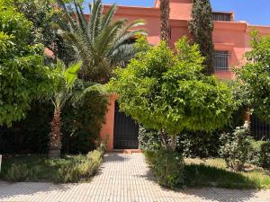 Villa Targa Piscine 10 minutes du centre في مراكش: منزل به اشجار وممر من الطوب