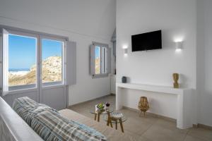a white living room with a couch and a tv at Spectacular view Caldera St V in Megalochori