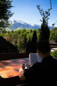 un homme assis sur un banc avec une tasse de café dans l'établissement Pensiunea Poiana Avrigului, à Avrig